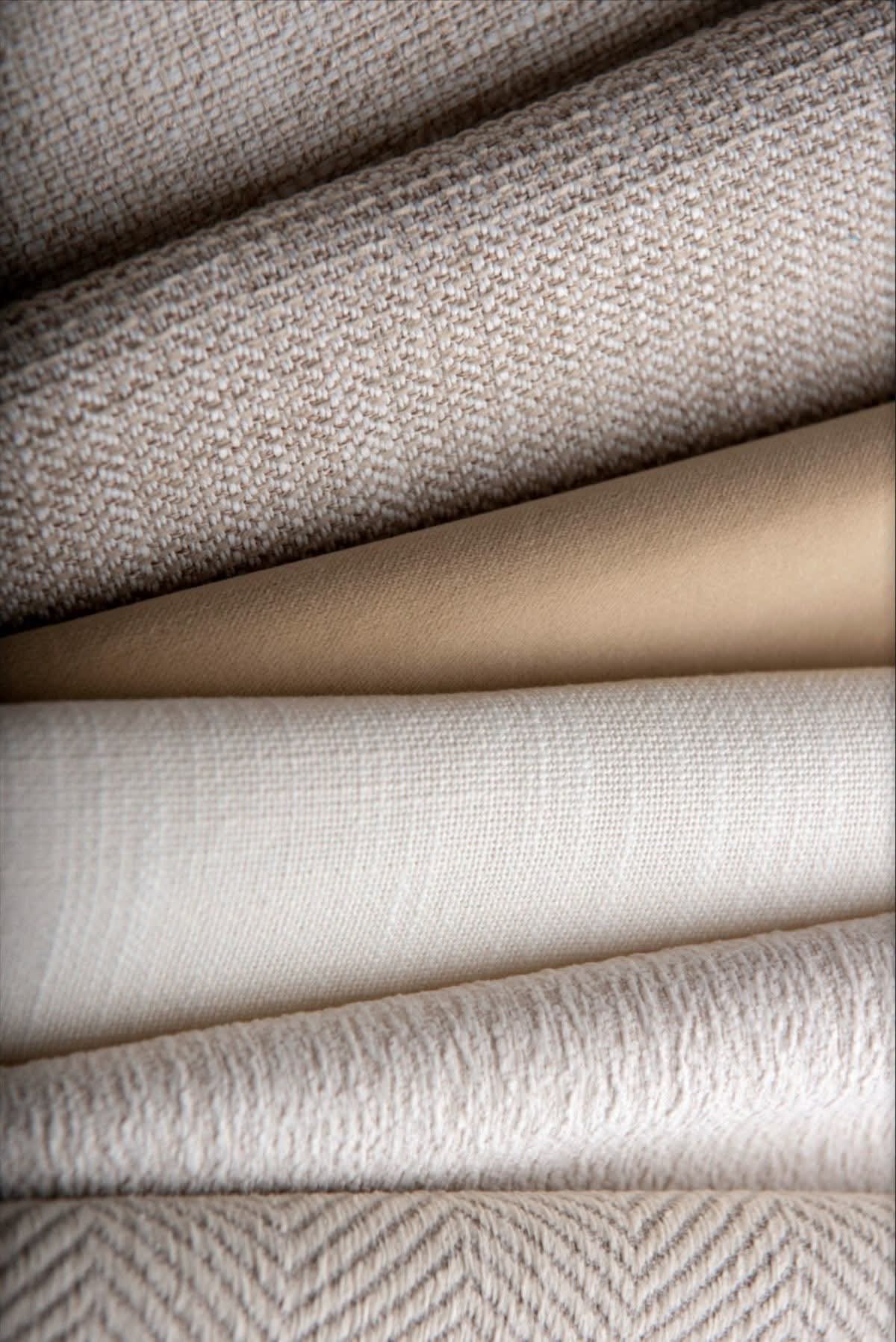 Stacked folds of undyed cotton and linen cloth in ivory, oat and stone