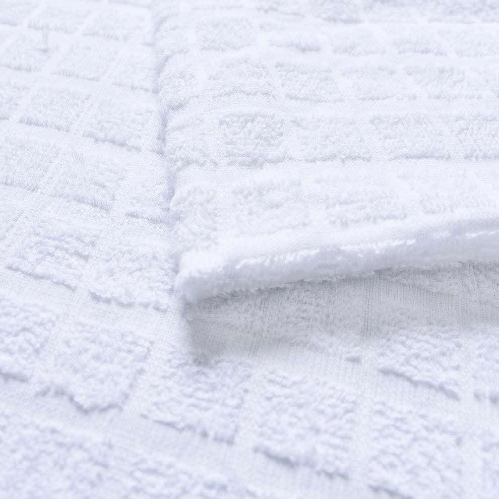 Macro detail of a white waffle-weave cotton towel showing the raised square cells